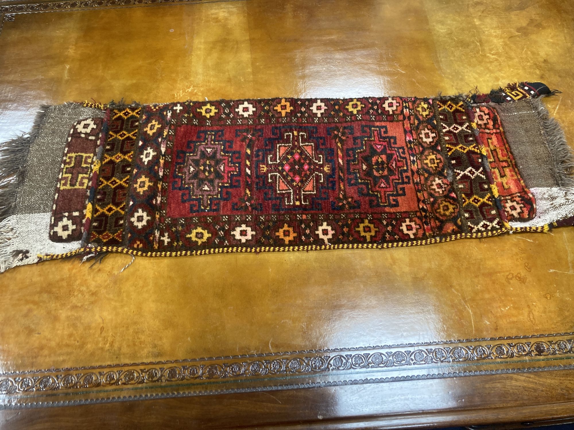 Six Caucasian design mats and a saddlebag, largest 140 x 60cm